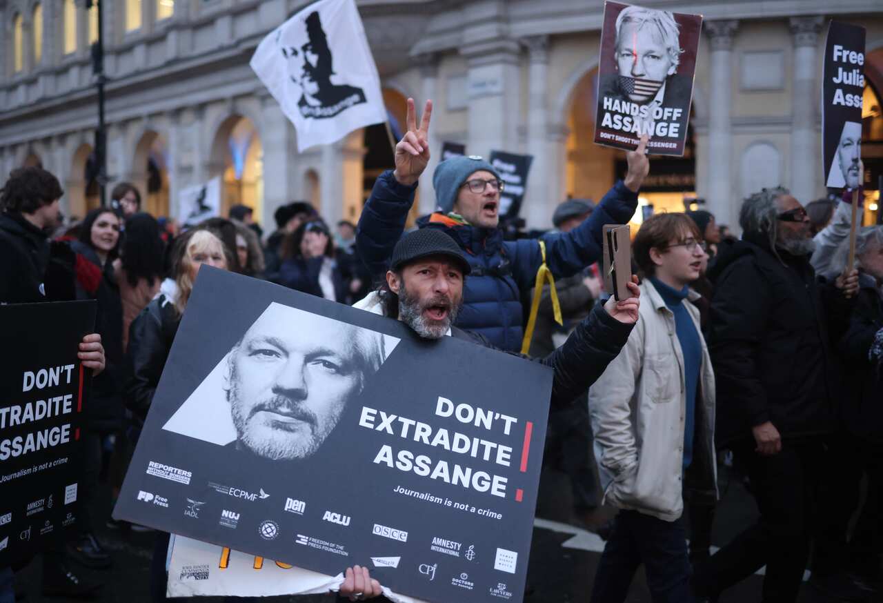 Group of people march holding signs in street.