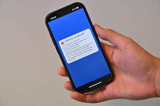 A person holding a smartphone displaying the AusAlert message.