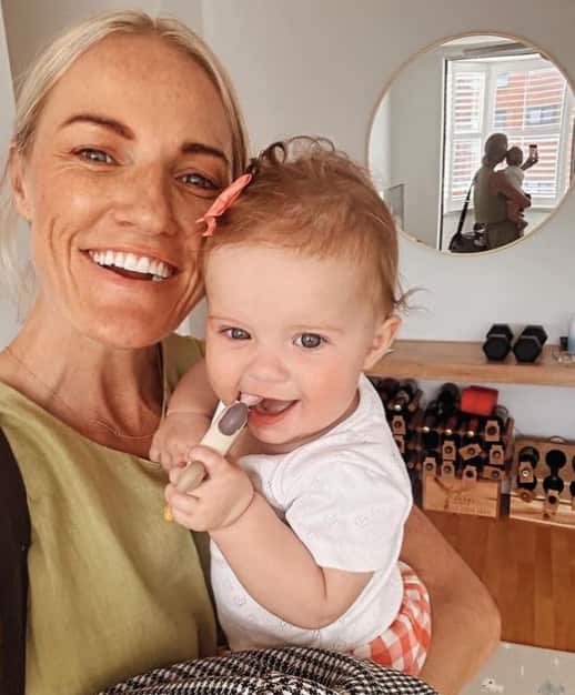 A smiling woman holds a baby in her arms.