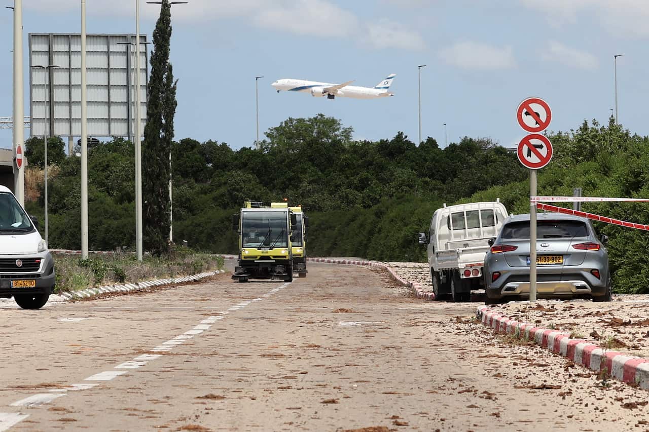 Two vehicles pass through a main road, with cars parked on either side.