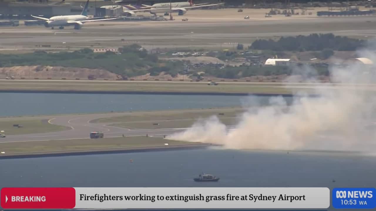 Smoke seen rising from grass at an airport.