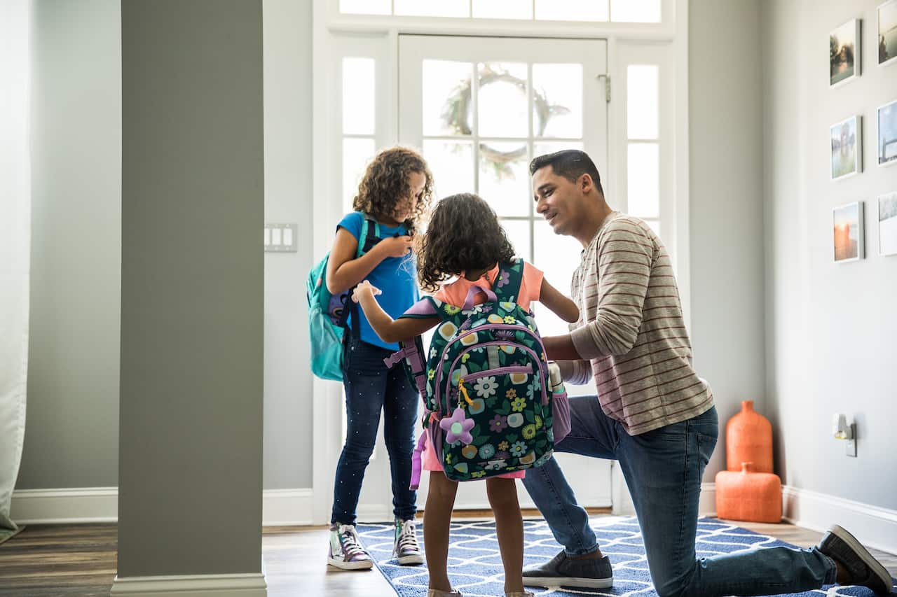 Father packing daughters backpacks for school