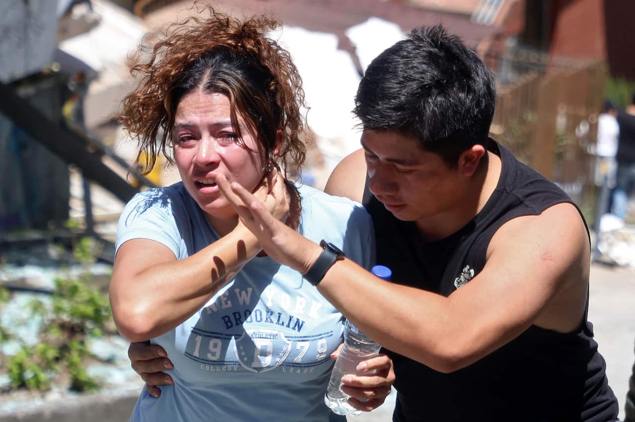 A woman wearing a blue T-shirt is being helped by a man wearing a black singlet