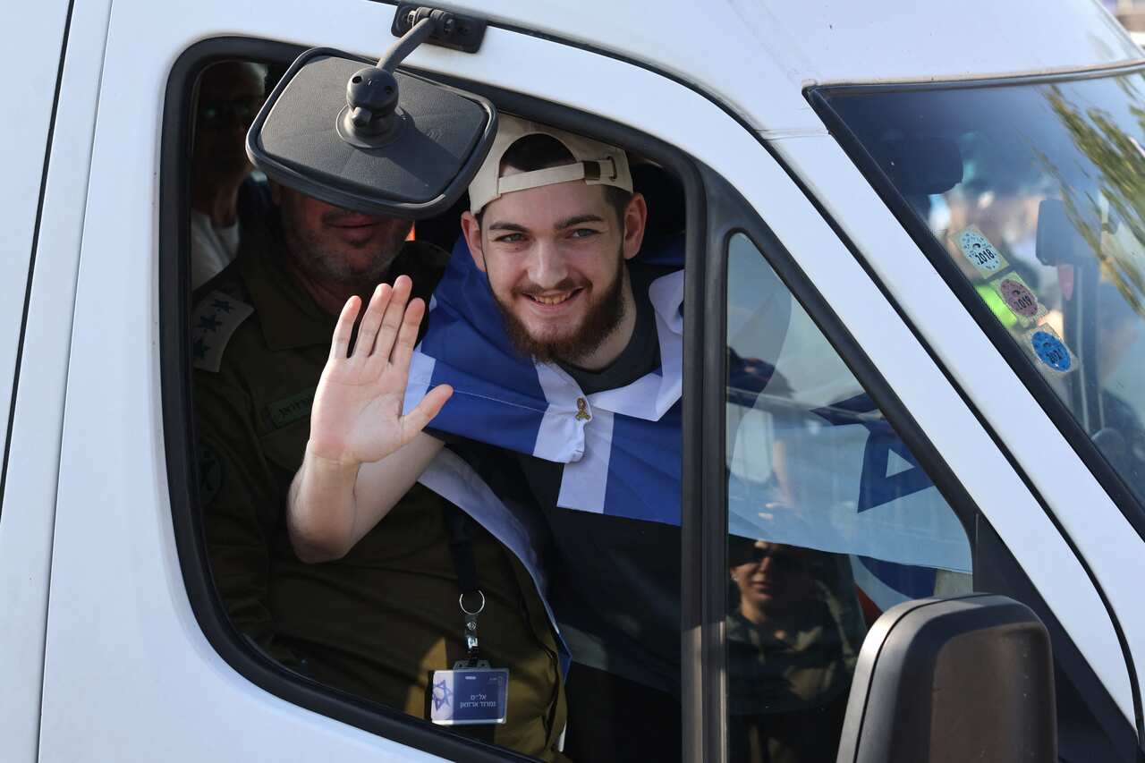 A man draped in an Israeli flag waving from a white van.