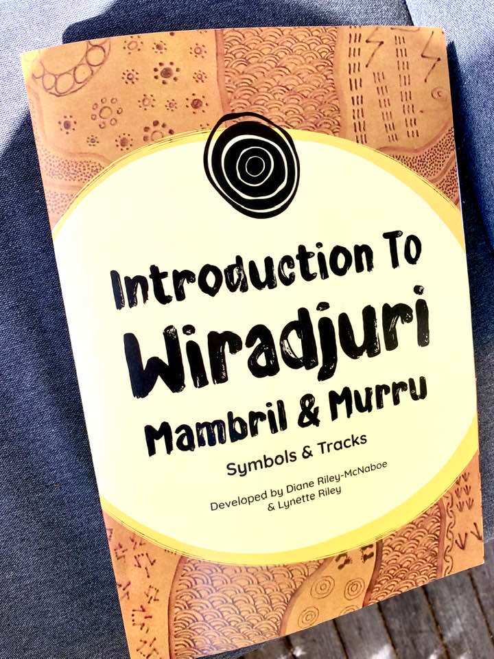 The cover of the Wiradjuri Workbooks features art and symbols in earthy colours