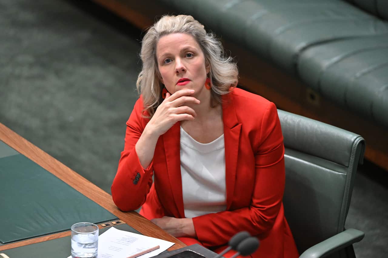 A woman in red suit looks on.