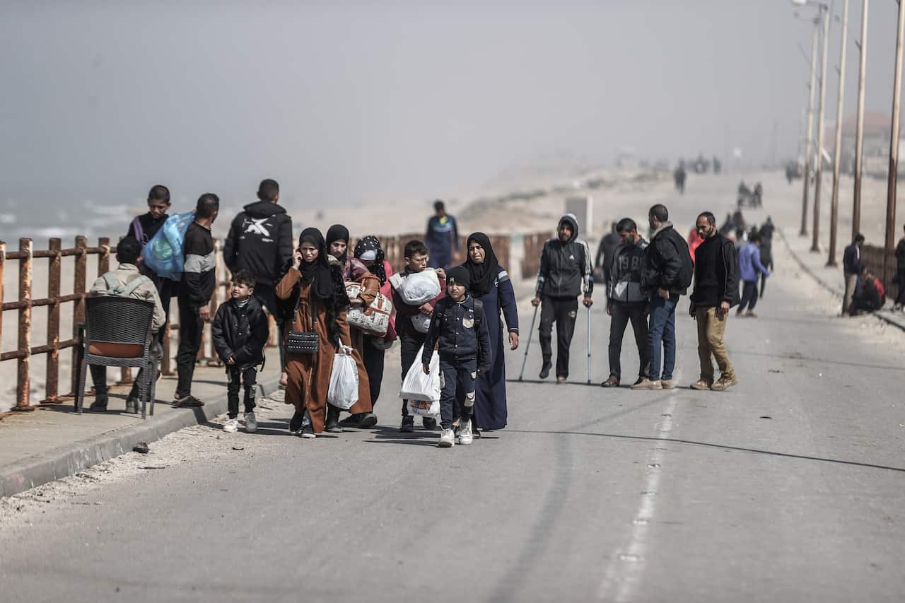 A group of Palestinians carrying bags walking along a road