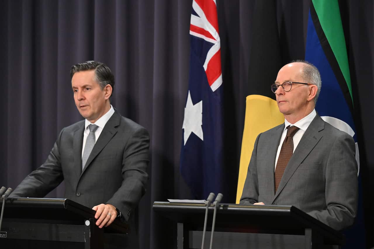 Two men in suits stand on a podium ready to speak