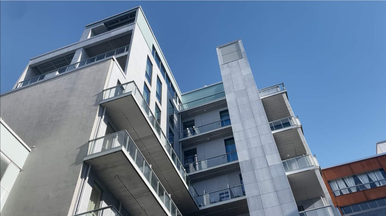 A view looking up toward a modern apartment building and a blue sky