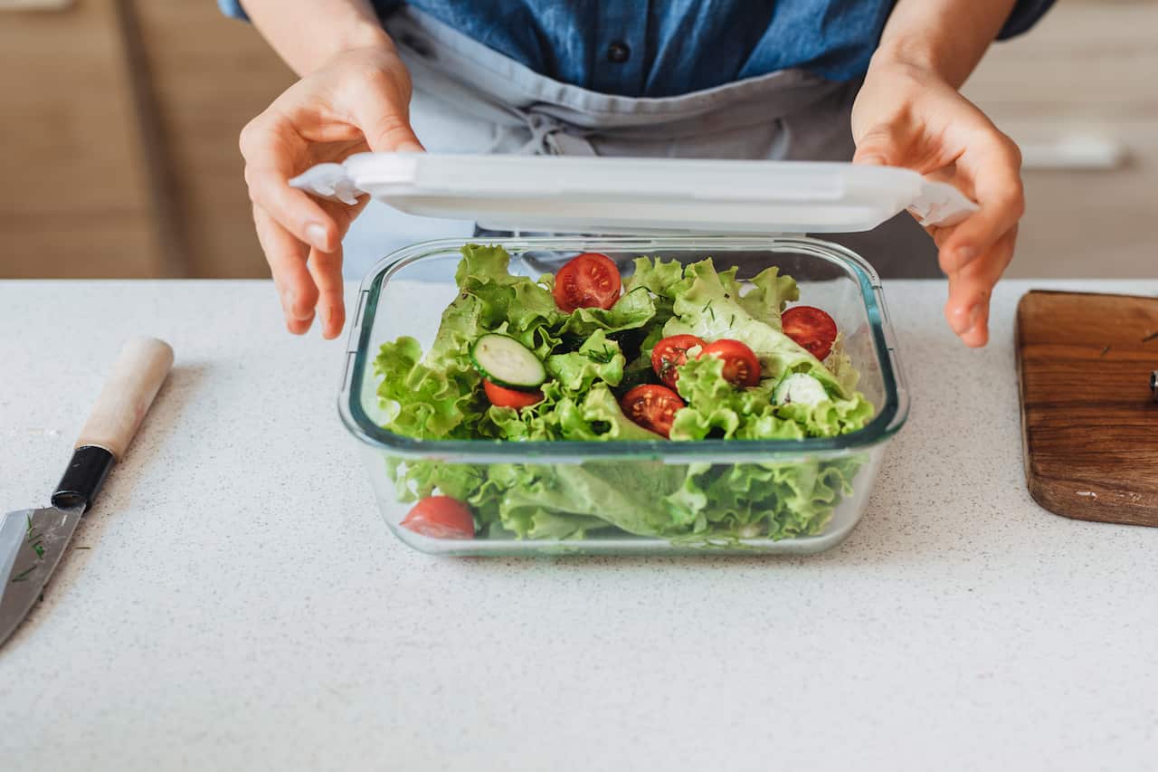 Hands of a Woman Packing a Healthy Salad into a Glass Container to be Taken Away