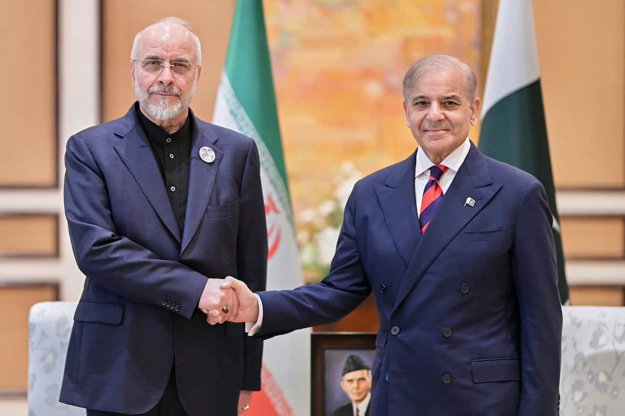 Mohammad Bagher Ghalibaf shaking hands with Pakistani Prime Minister Shehbaz Sharif in a room with the Iranian and Pakistani flags.