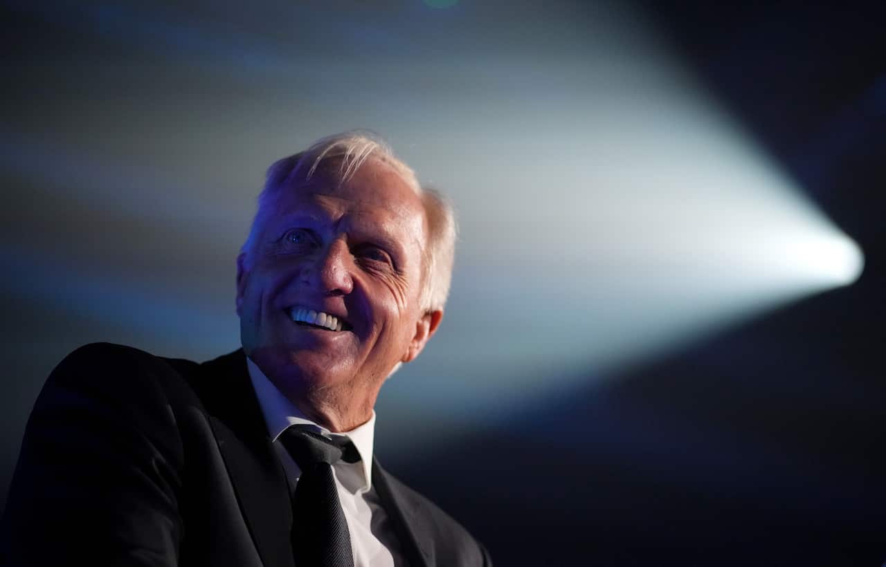 Greg Norman smiles while a spotlight is placed on him