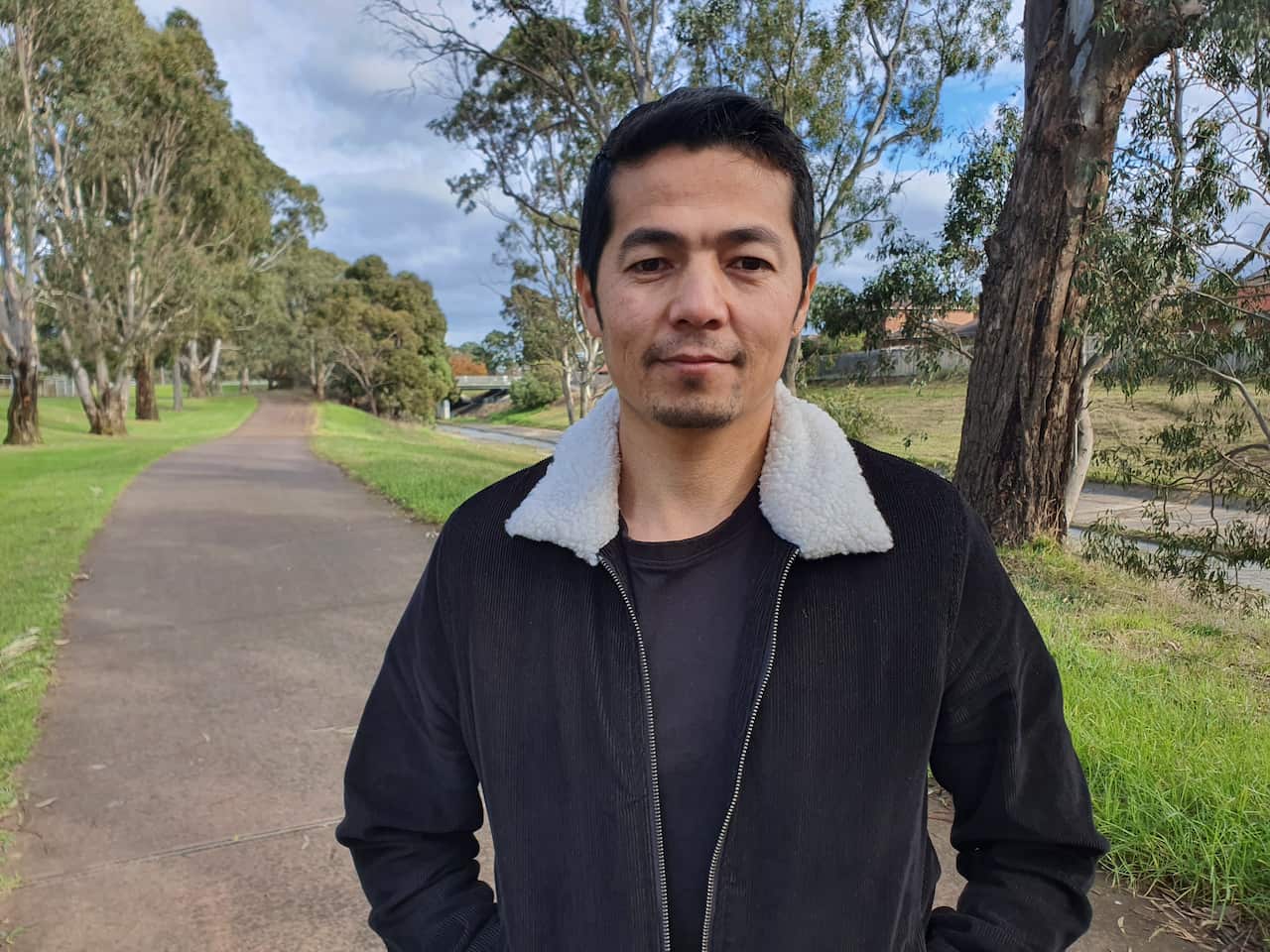 An Afghan man wears a black jacket with a white fluffy collar