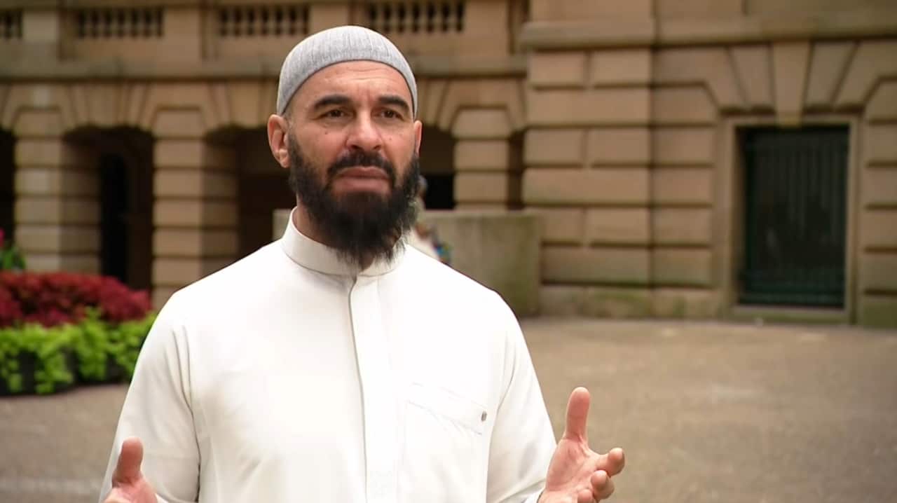 A man wearing a white shirt speaking.