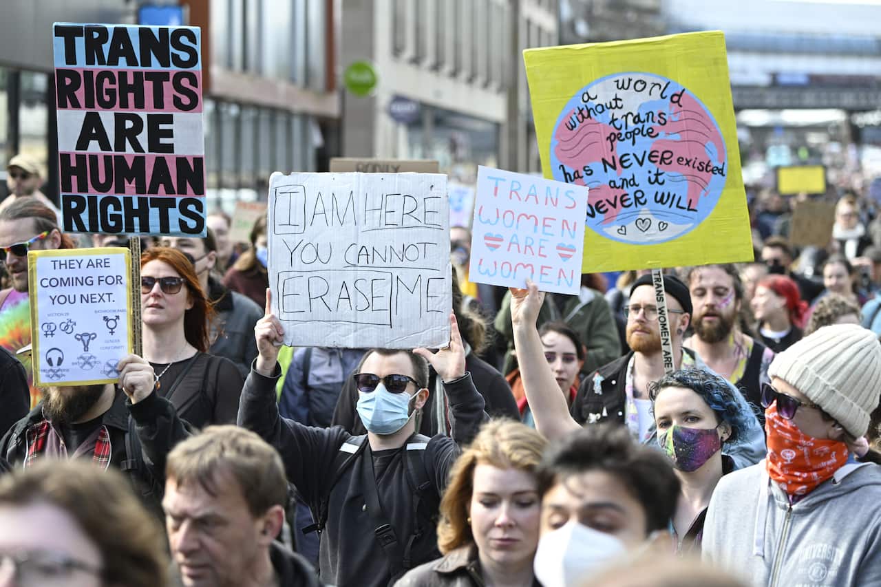 A large group of protesters holding up signs with pro-trans messages.