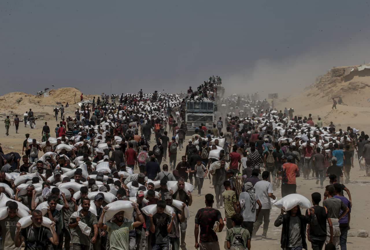 A group of people carrying bags of flour over their shoulders