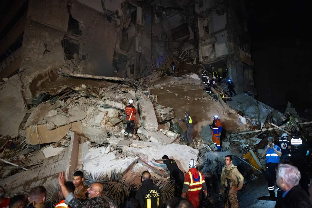 Rescue workers searching through the rubble of a heavily damaged building.
