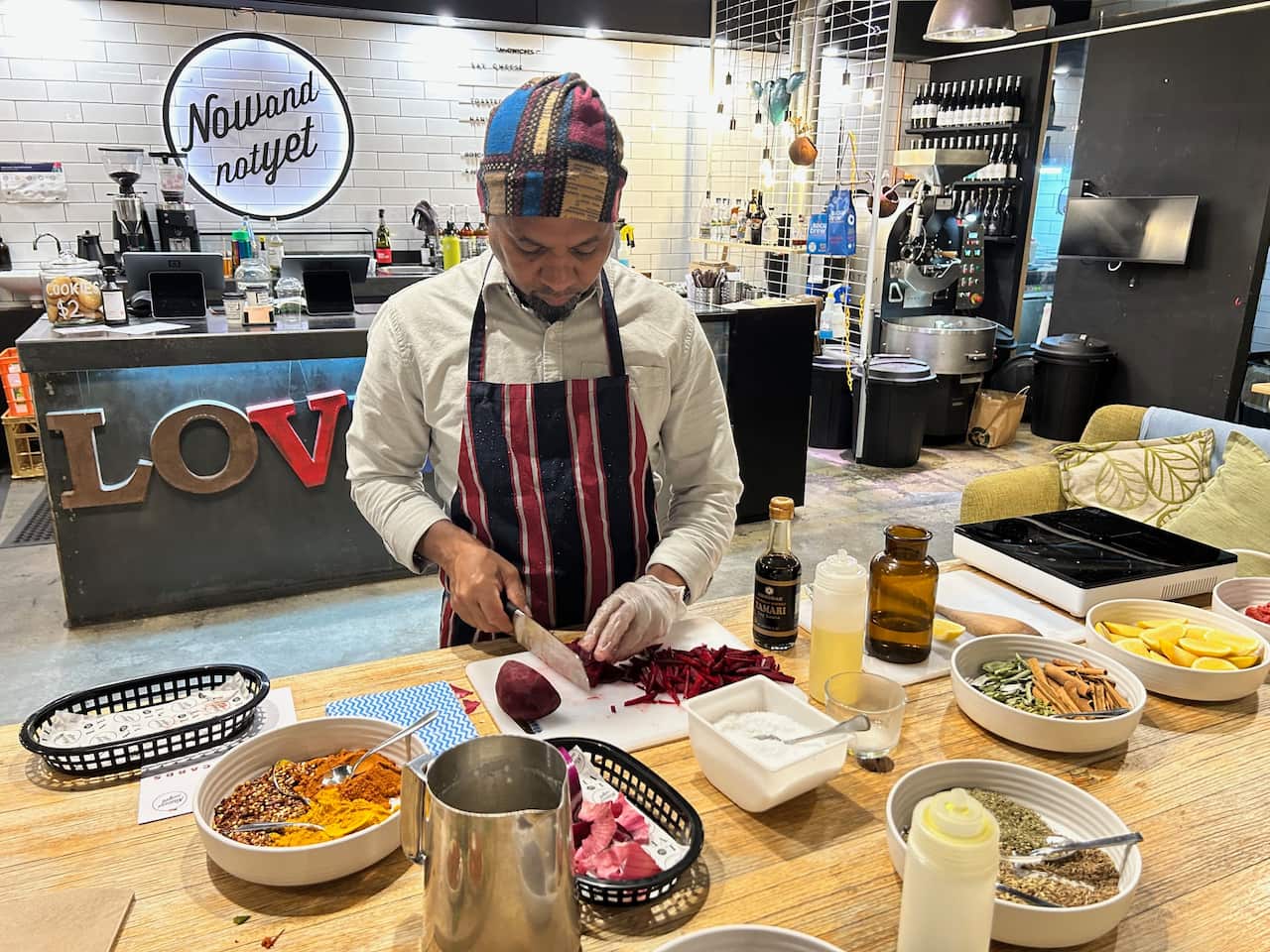 A man in a striped apron stands at a bench preparing food.