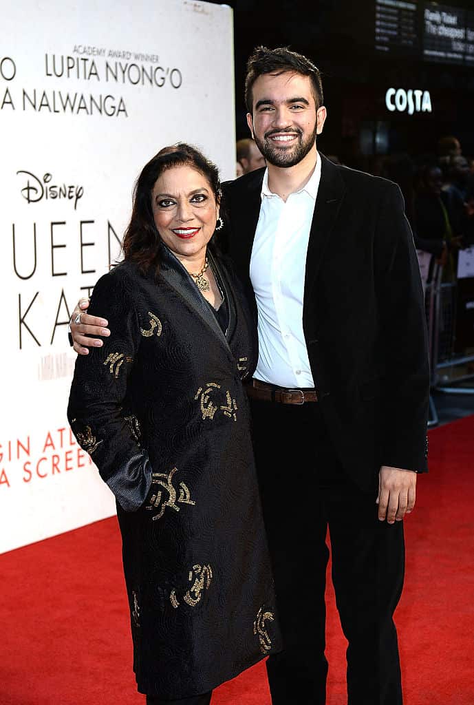 A man stands with his arm around an older woman on the red carpet.