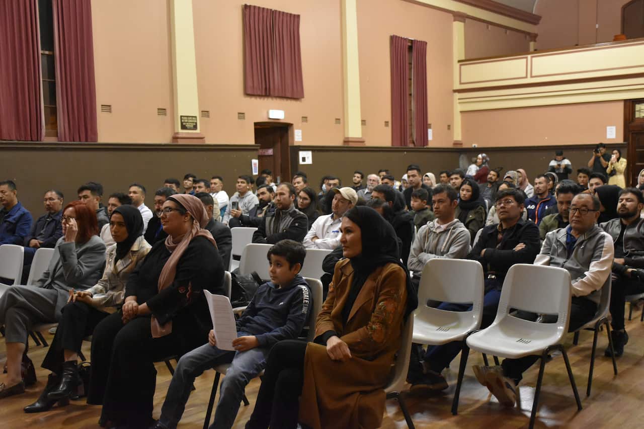 People sit on chairs looking ahead in a hall. 