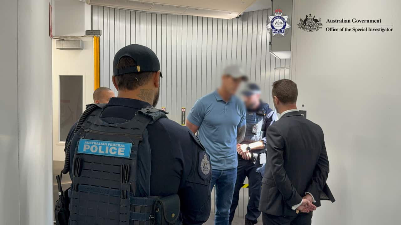 Police officers speaking to a man.