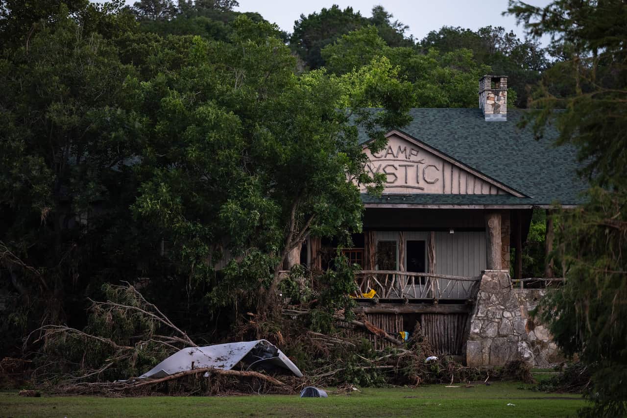 Debris scattered around near a building with a sign that says "Camp Mystic".