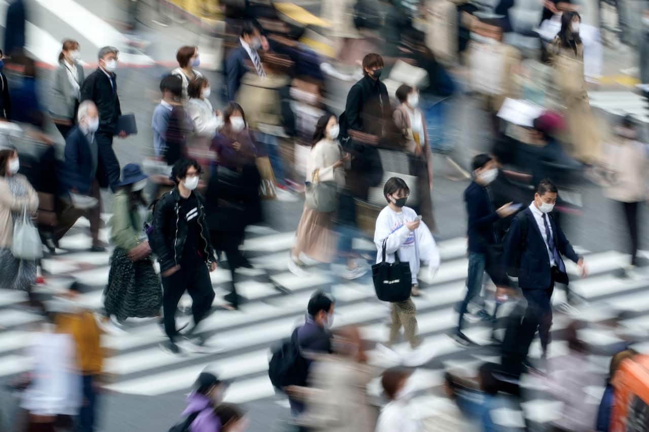 Pedestrians walk through Shibuya's busy scramble crossing in Tokyo.