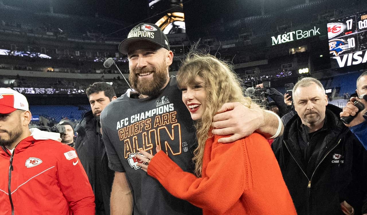 A man with his arm wrapped around a woman, both smiling.