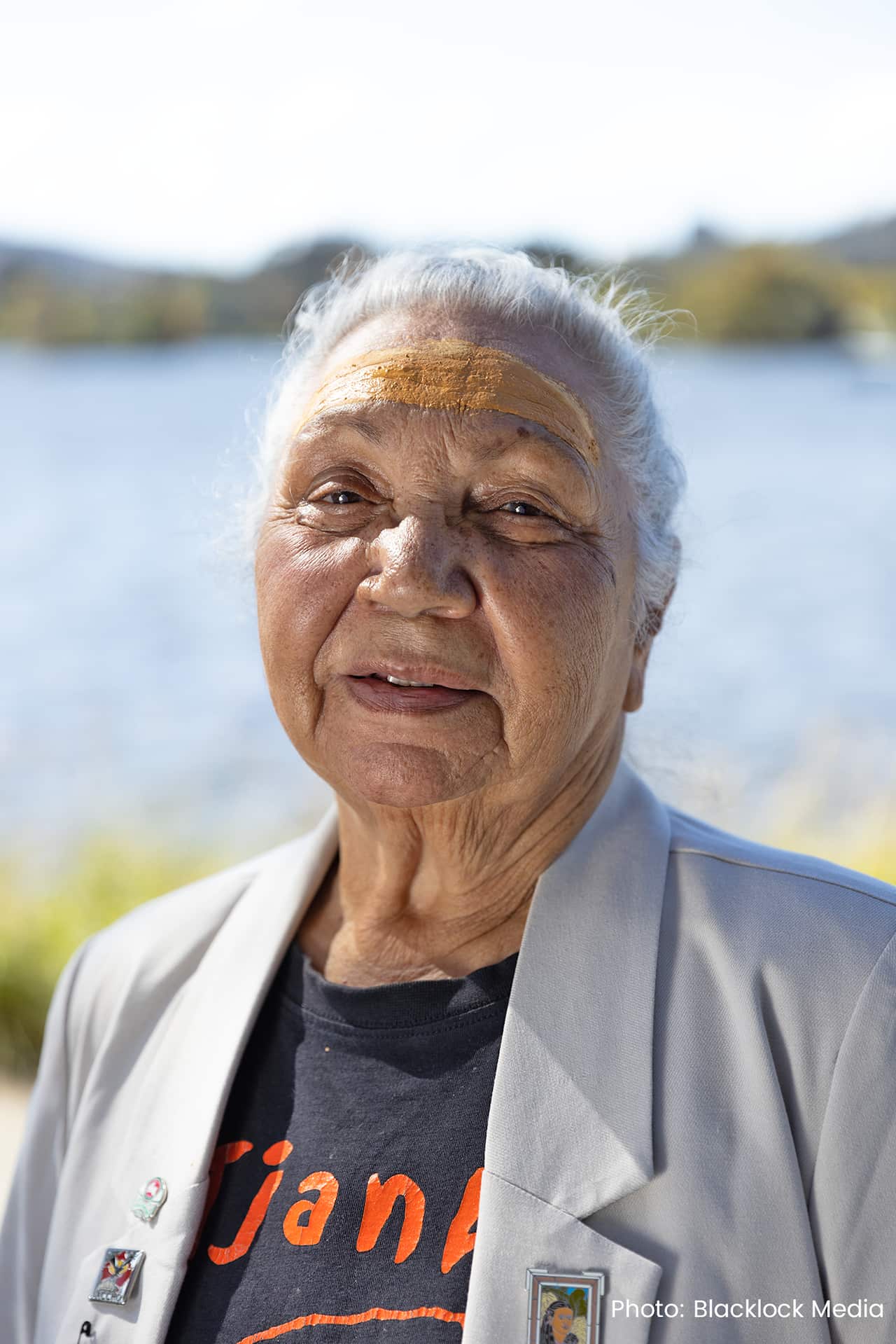 A portrait of a woman looking at the camera with water in the background.