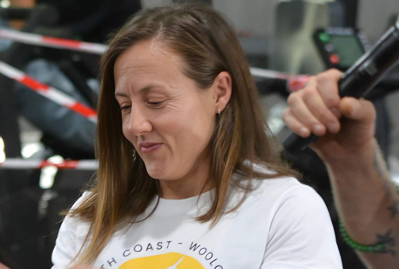 Close-up of a woman in a white t-shirt inside a gym.