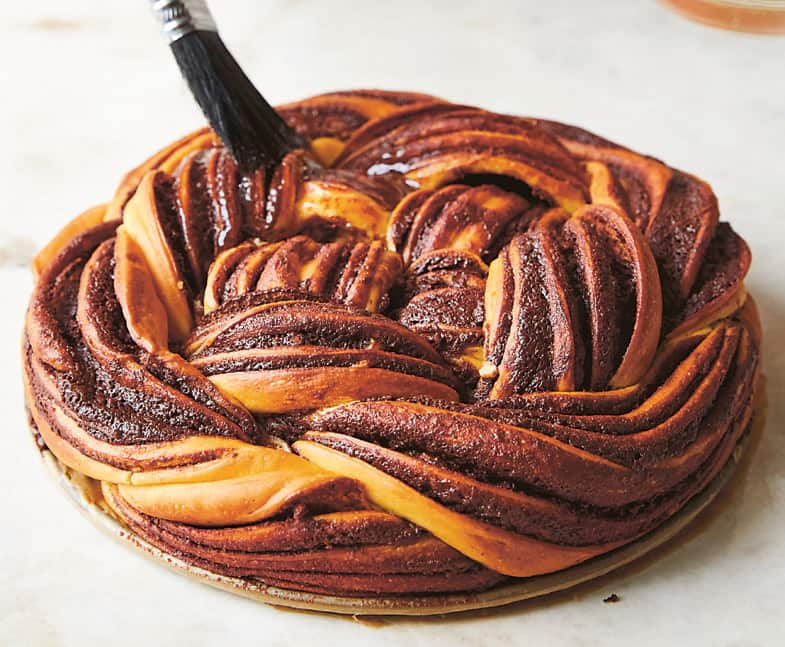 A baked babka knot is brushed with syrup. 