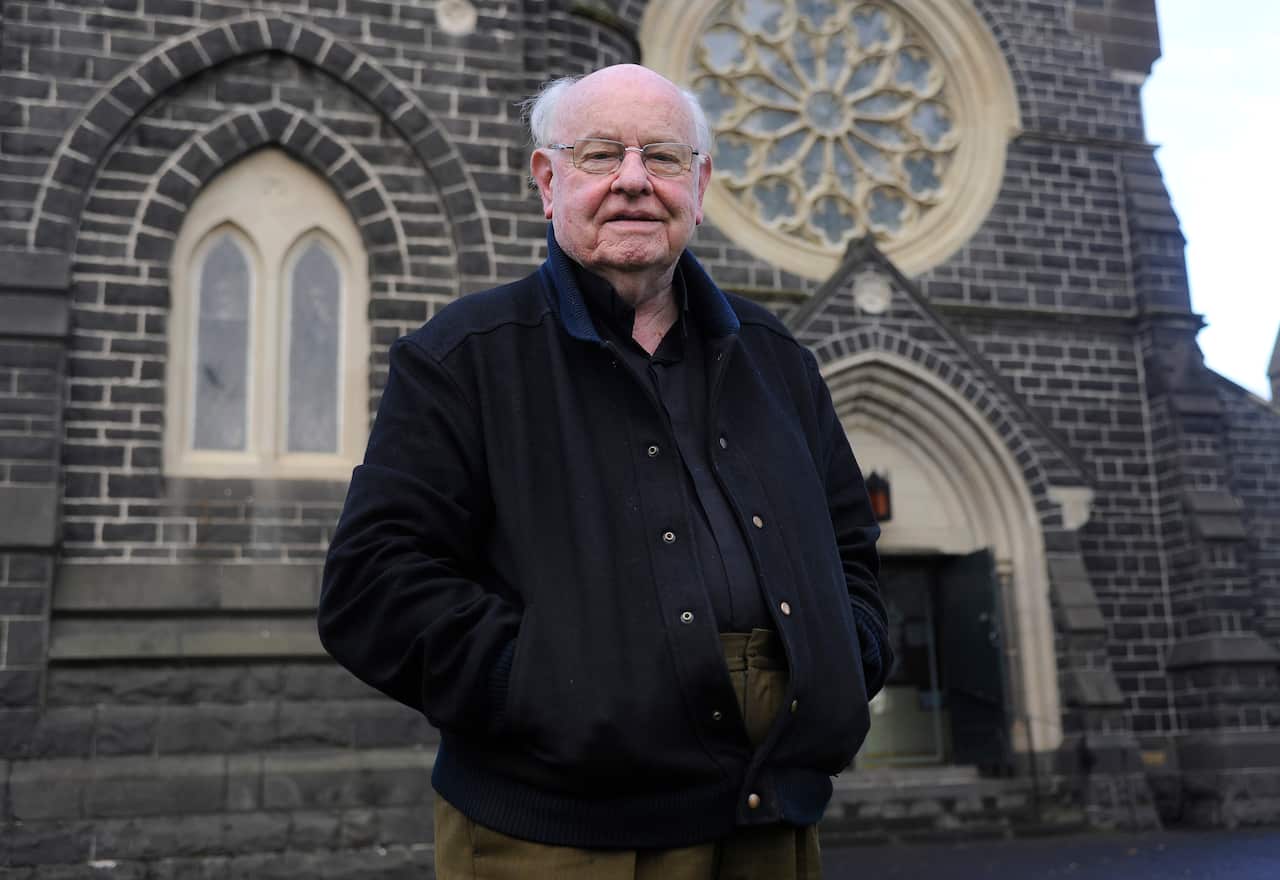 Father Bob Maguire standing outside a church.