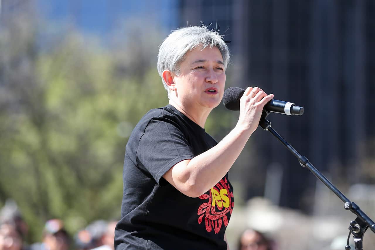 Penny Wong wearing a 'Yes' tshirt speaking into a microphone.