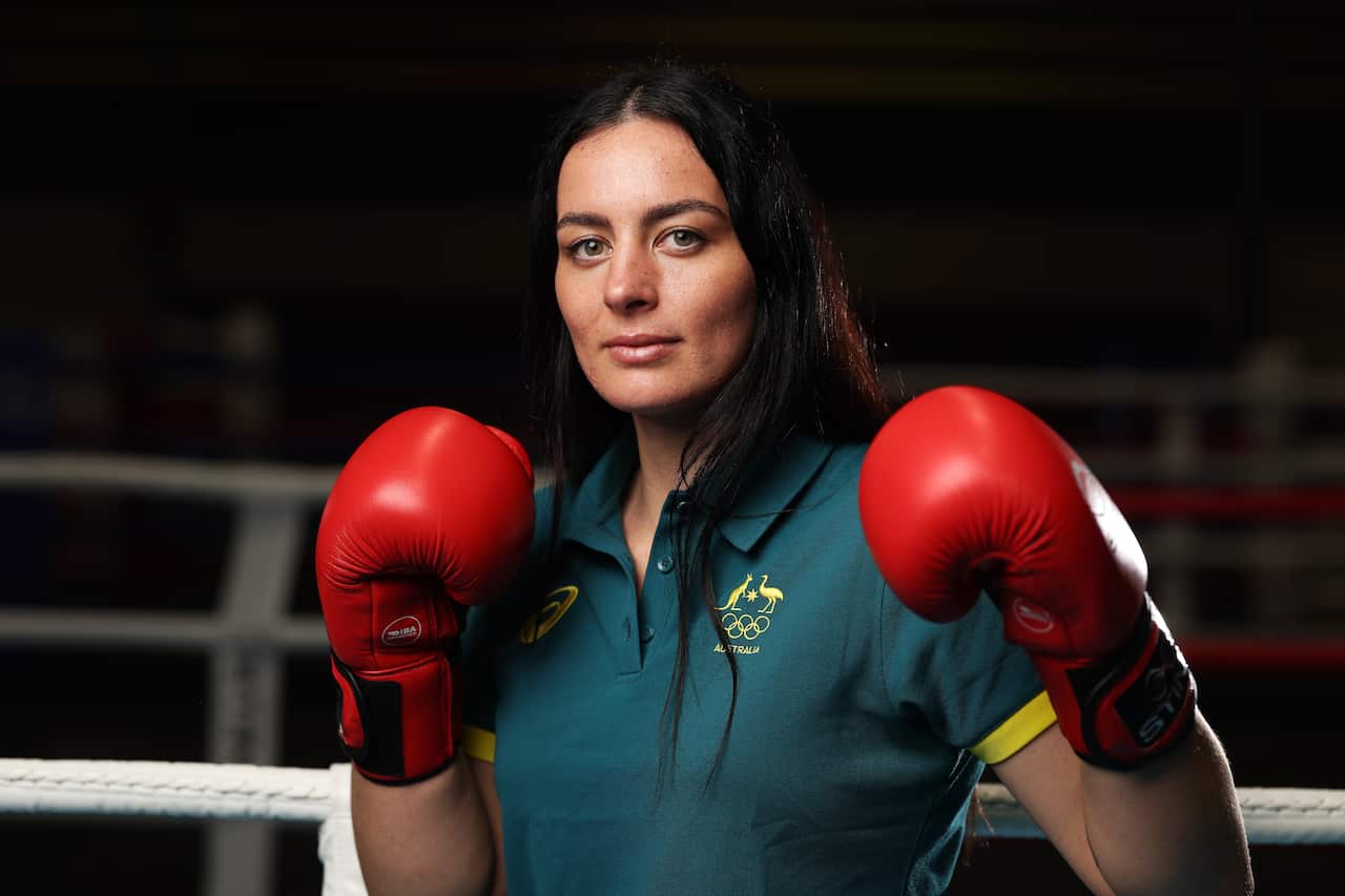 A woman stands with red boxing gloves