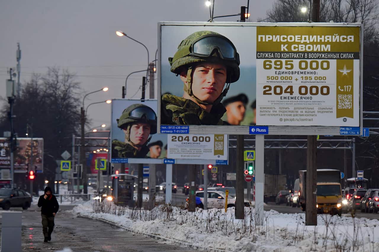 A man walks past billboards promoting contract army service in Russia.