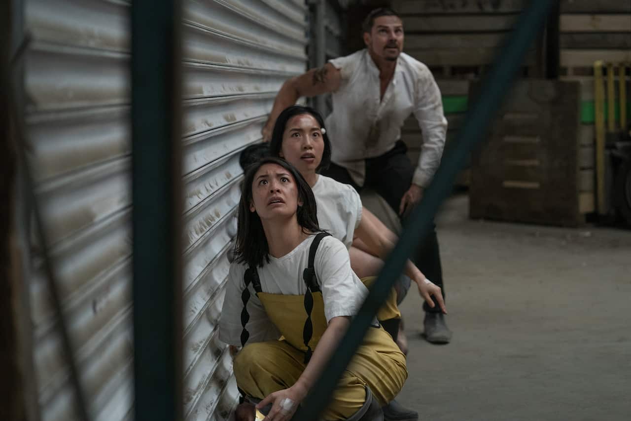 New Zealand actors JJ Fong, Perlina Lau and Jay Ryan crouch down and look scared as they look up at an unseen threat in a garage in season 2 of Creamerie.jpeg