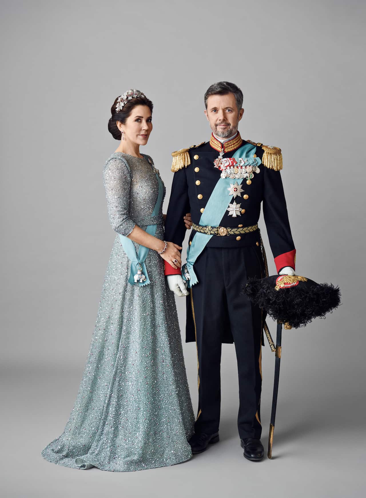 Crown Princess Mary and Crown Prince Frederik posing in front of a grey background.