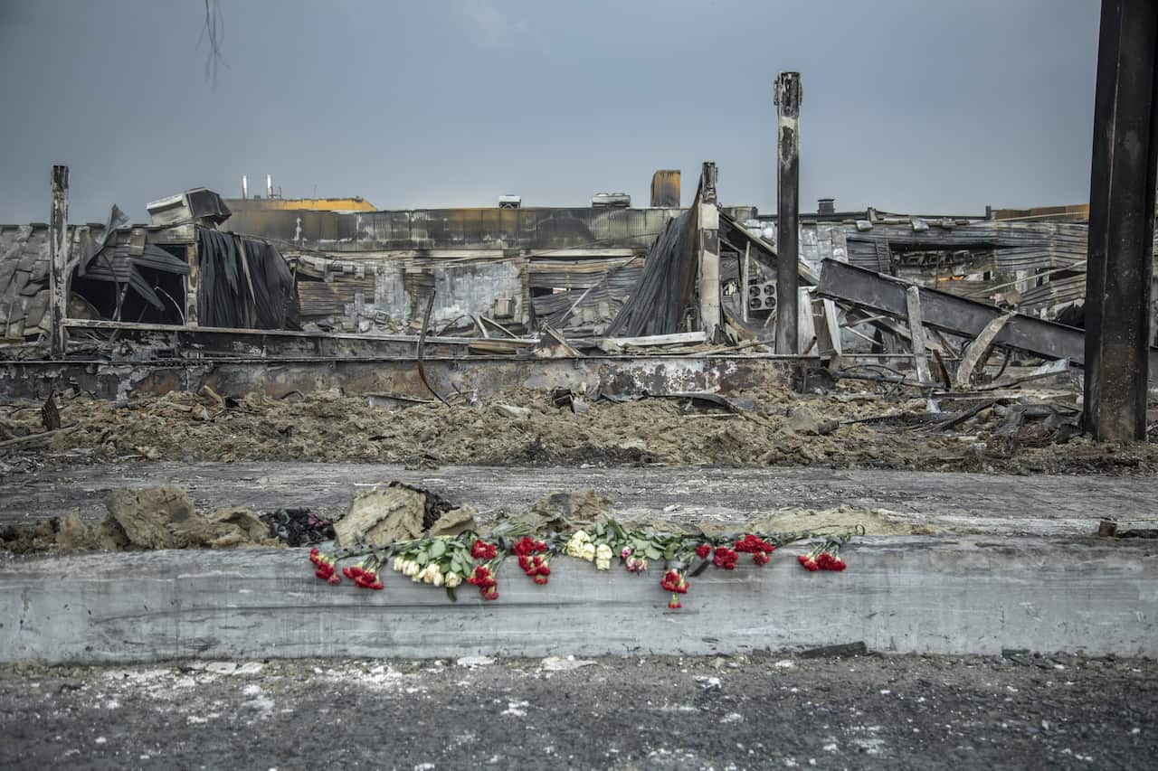 Flowers on a pavement with a destroyed building in the background.