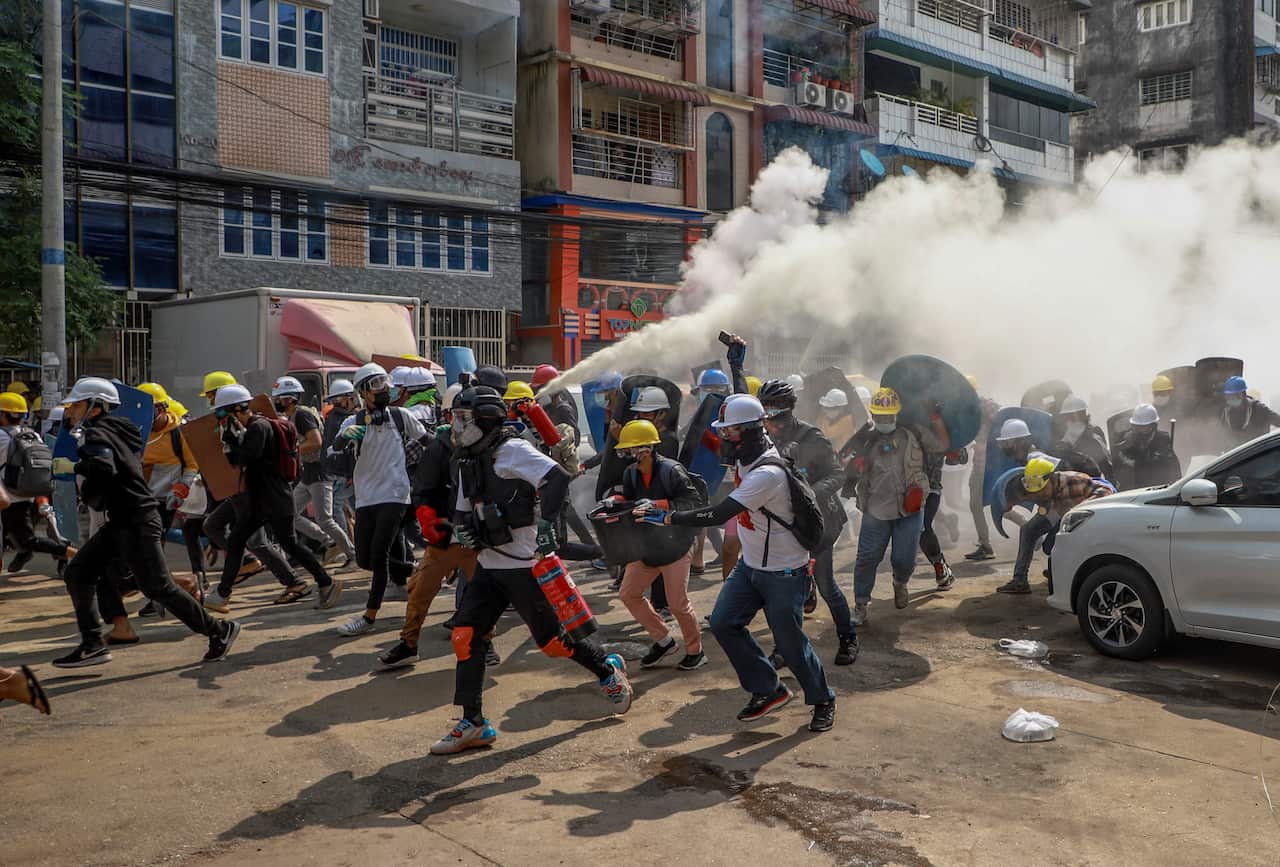Myanmar protesters wearing helmets in the street.