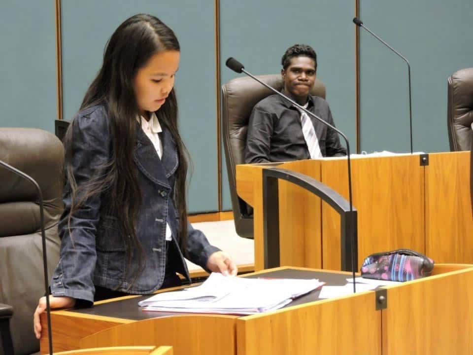 Young people speaking in a parliament setting 