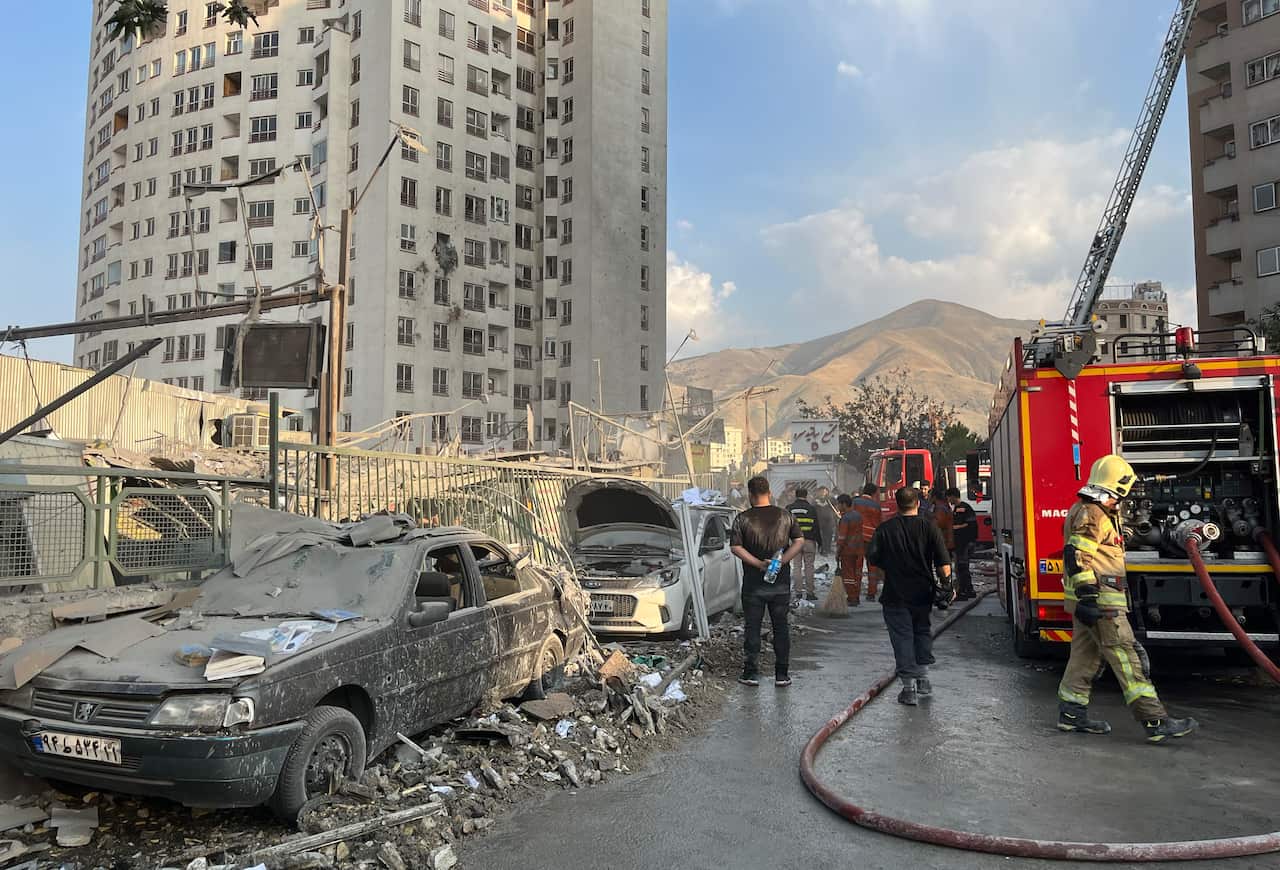 A firetruck parked next to bombed out cars and buildings surrounded by rubble