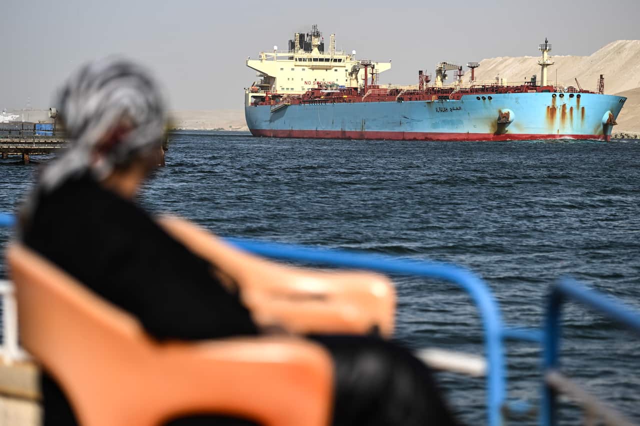 A person watches as a ship crosses the Suez Canal towards the Red Sea in Ismailia, Egypt.