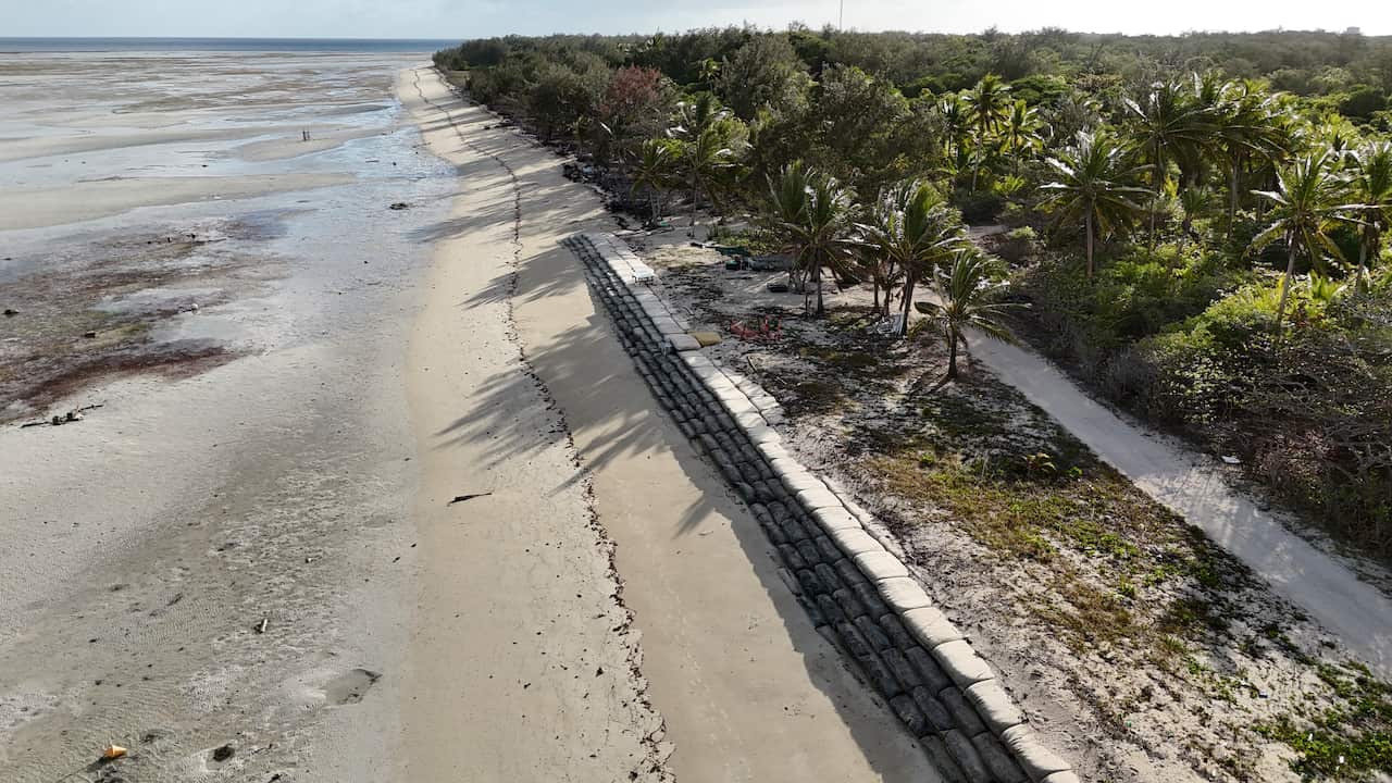 A drone shot of hundreds of sandbags lining a beach on Masig Island.