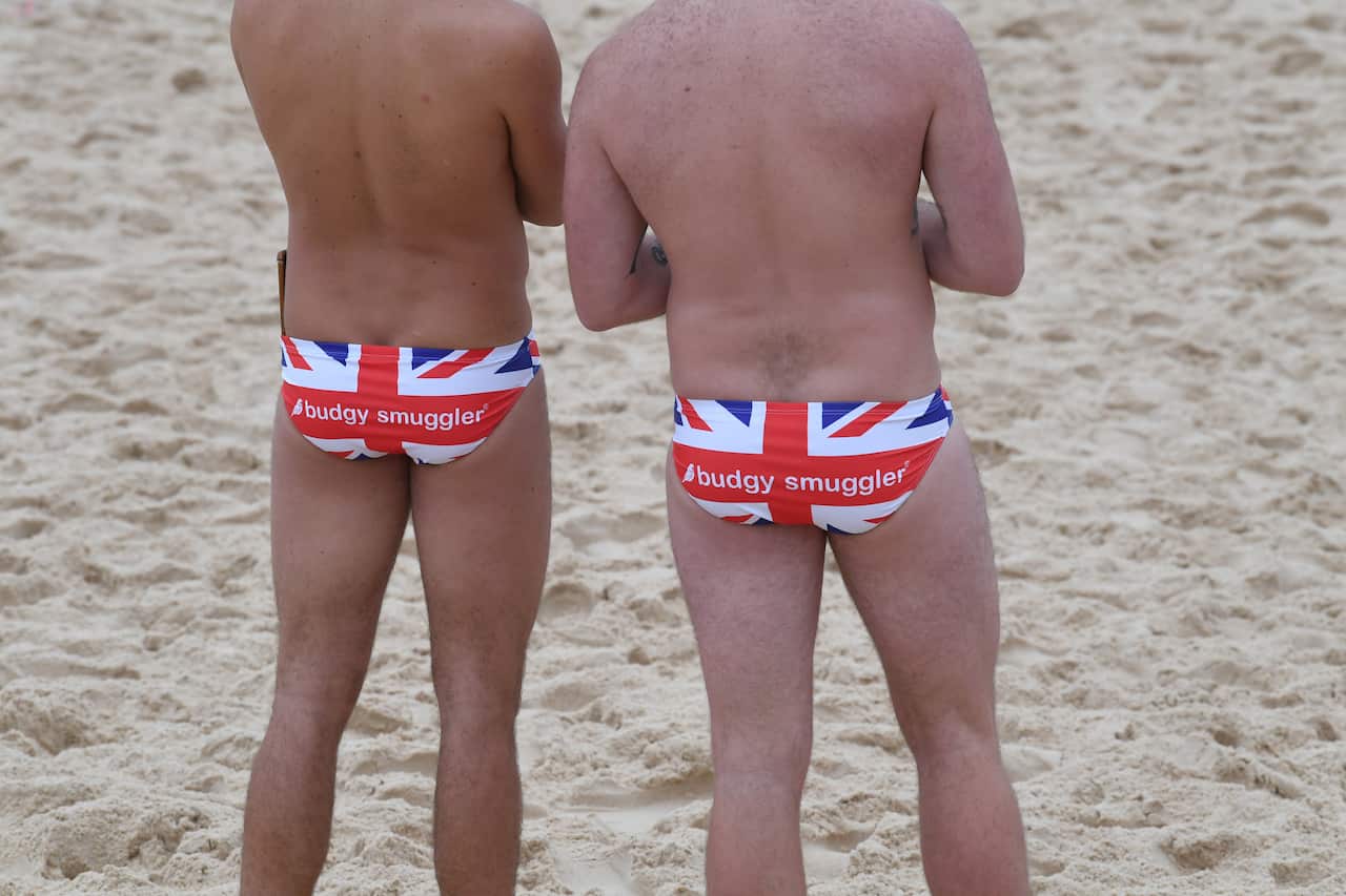 Rear view of two men standing on a beach and wearing swimwear featuring a Union Jack design