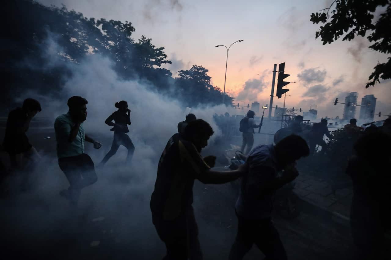 Protesters take cover as security forces fire tear gas during an anti-government protest rally in Colombo.