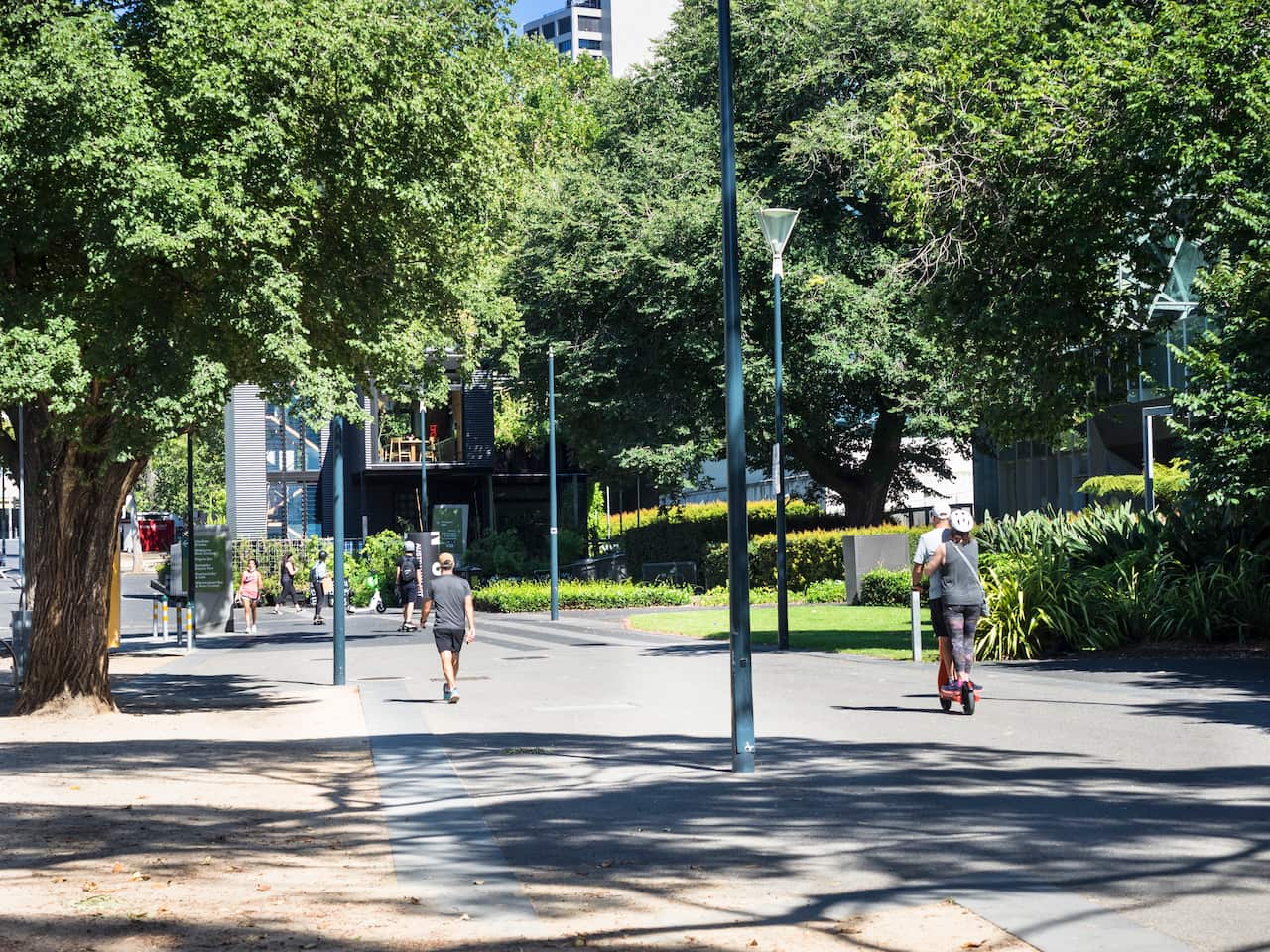 Two people on the one e-scooter, travelling on a shared path.