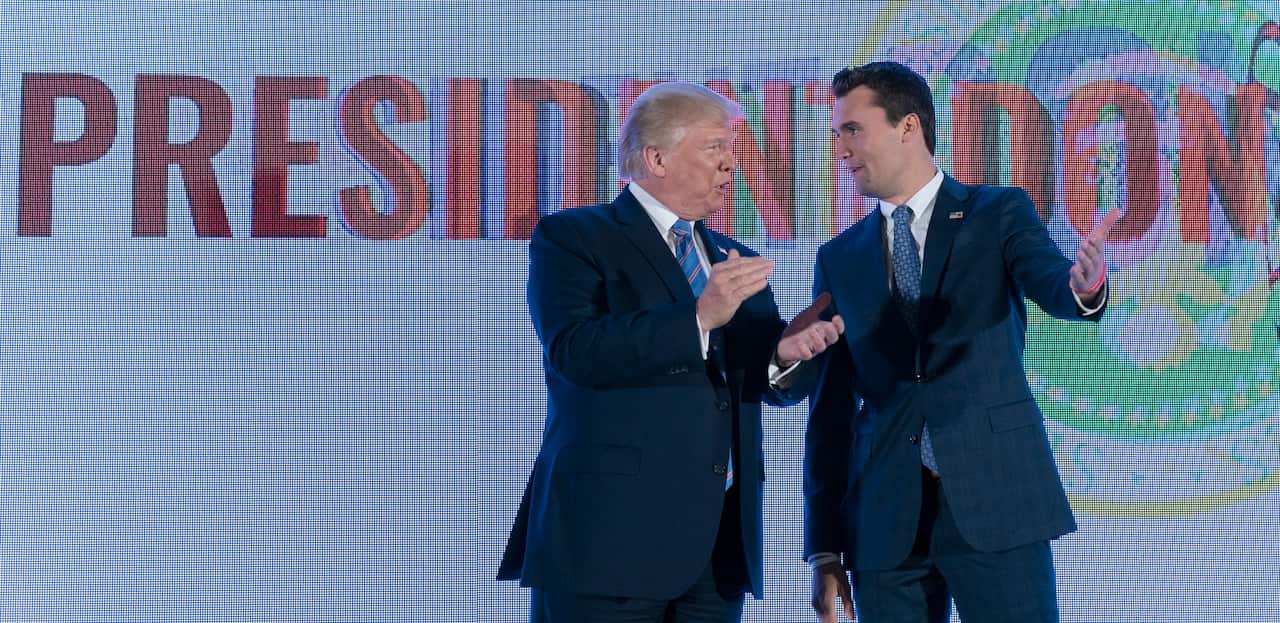 A man in a suit claps as he is greeted by another man in a suit