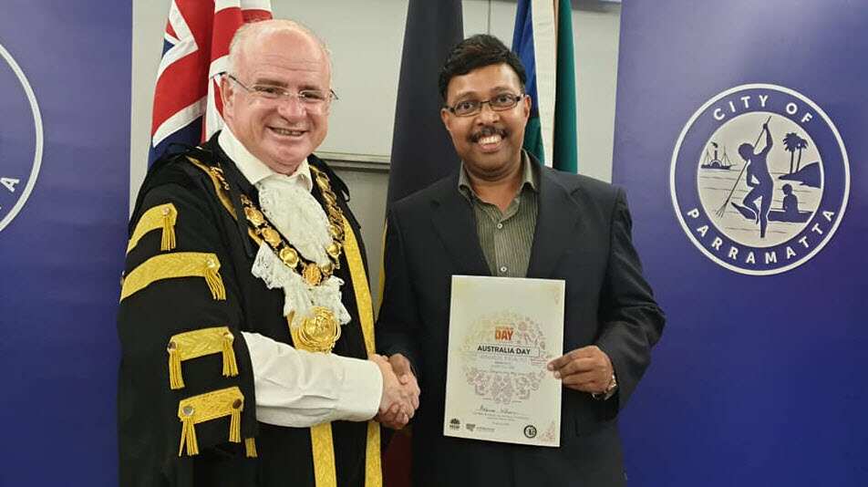 Two men shaking hands at a citizenship ceremony. 