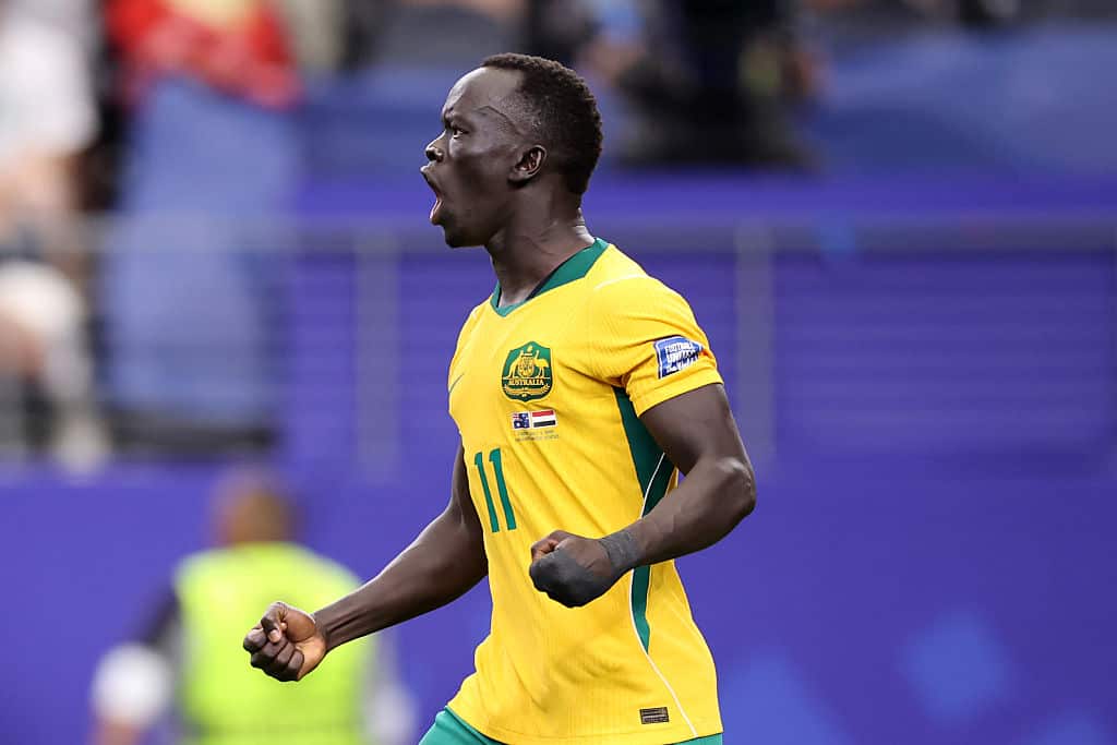 A man in a yellow football jersey celebrates after scoring a goal