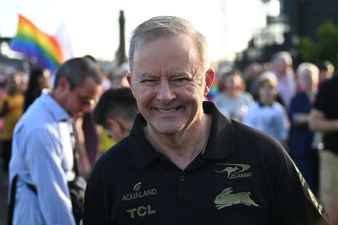 Man smiles on bridge at parade.